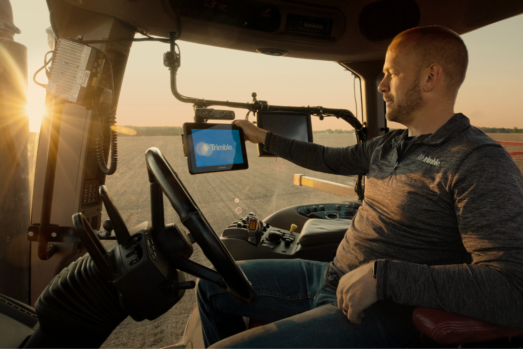 Farmer starts up Trimble GFX-1060 display in his tractor while sun rises in the background.